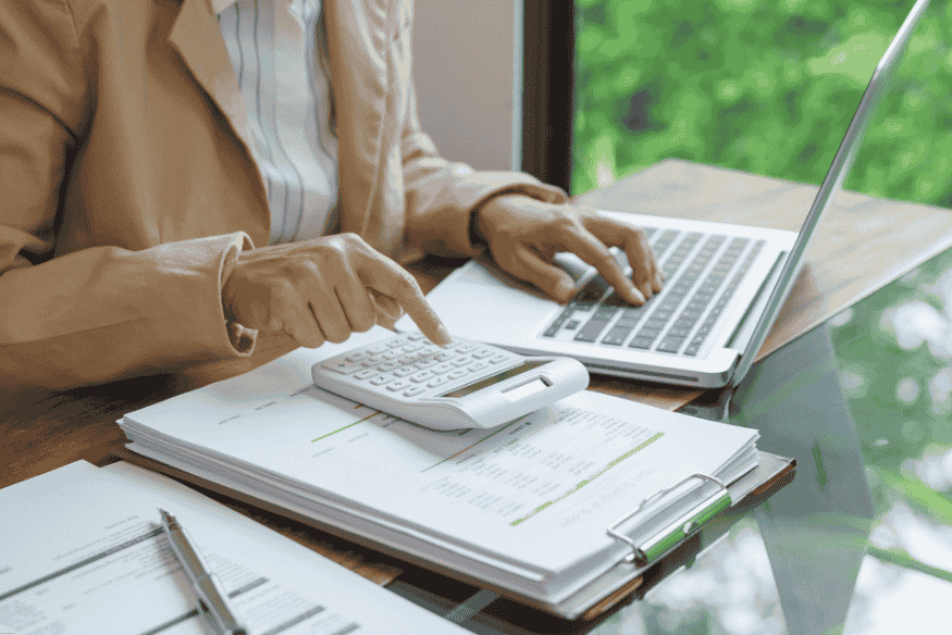 Investor calculating Sharia-compliant portfolio performance using laptop and documents