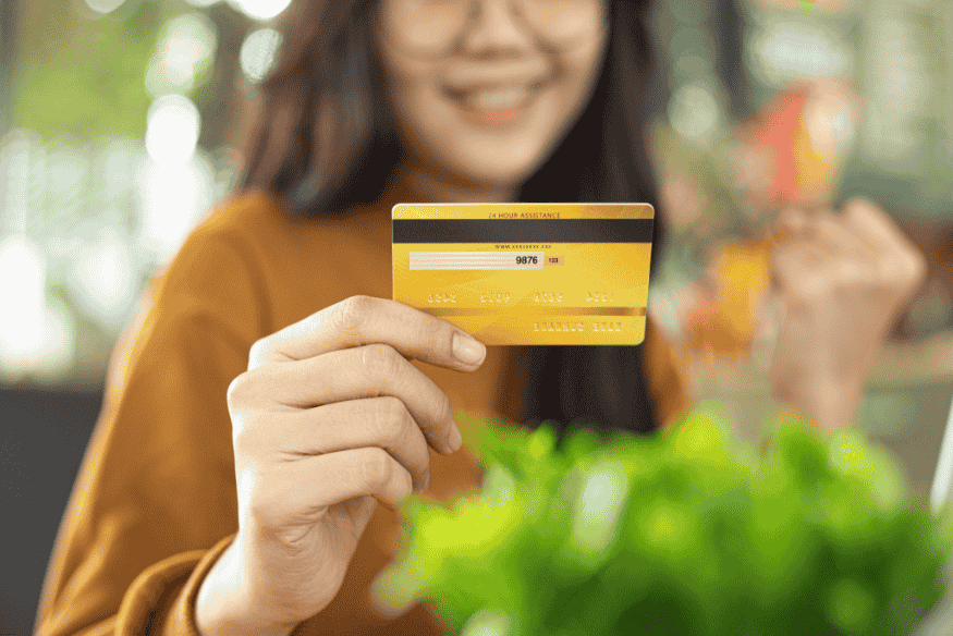 Woman holding a gold credit card and smiling after a successful purchase