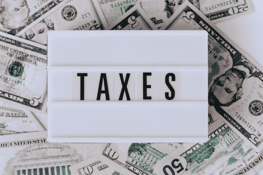 Word “TAXES” on a lightbox placed over US dollar bills.