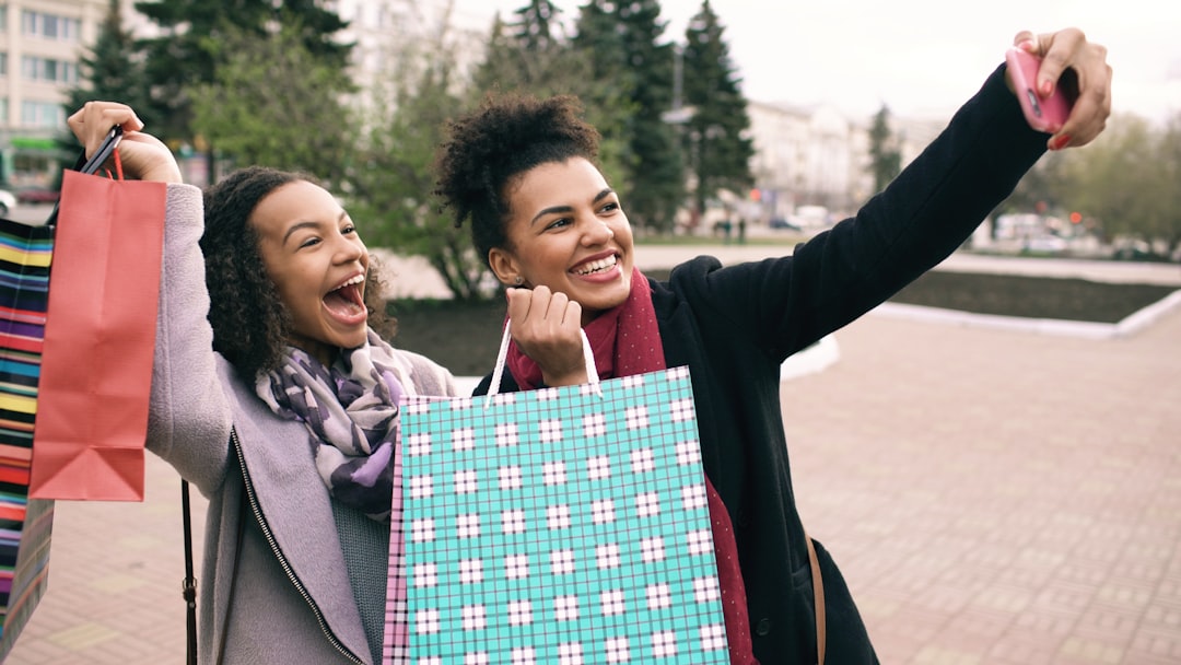Two happy women taking a selfie with shopping bags.