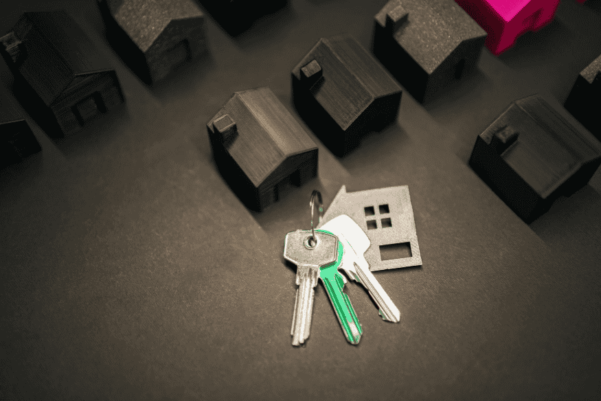 Keys on a dark table surrounded by miniature black houses
