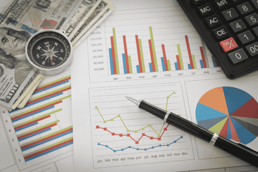 Financial charts, compass, US dollar bills, and calculator symbolizing global financial planning.