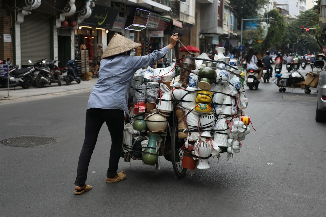 a woman pushing a cart full of items down a street