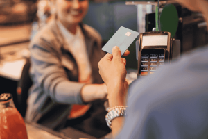 Customer using a blue credit card for a contactless payment at a café counter