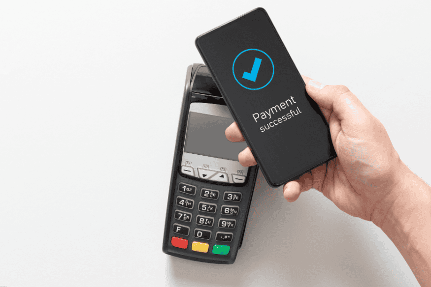 Hand holding smartphone showing “Payment successful” message after contactless payment.